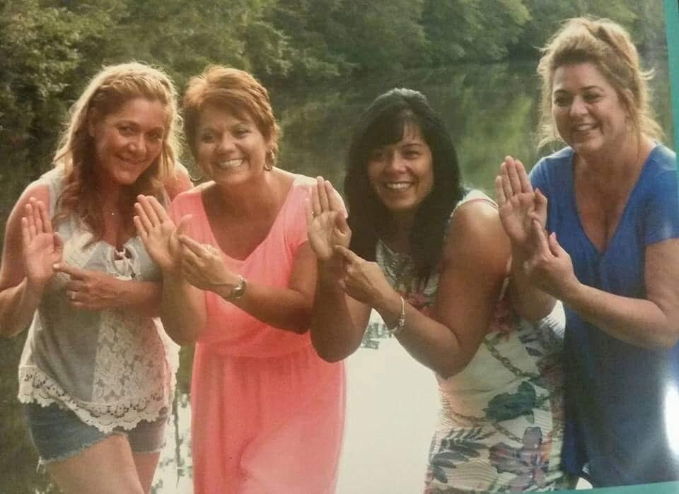 Four women outdoors pointing at their hands